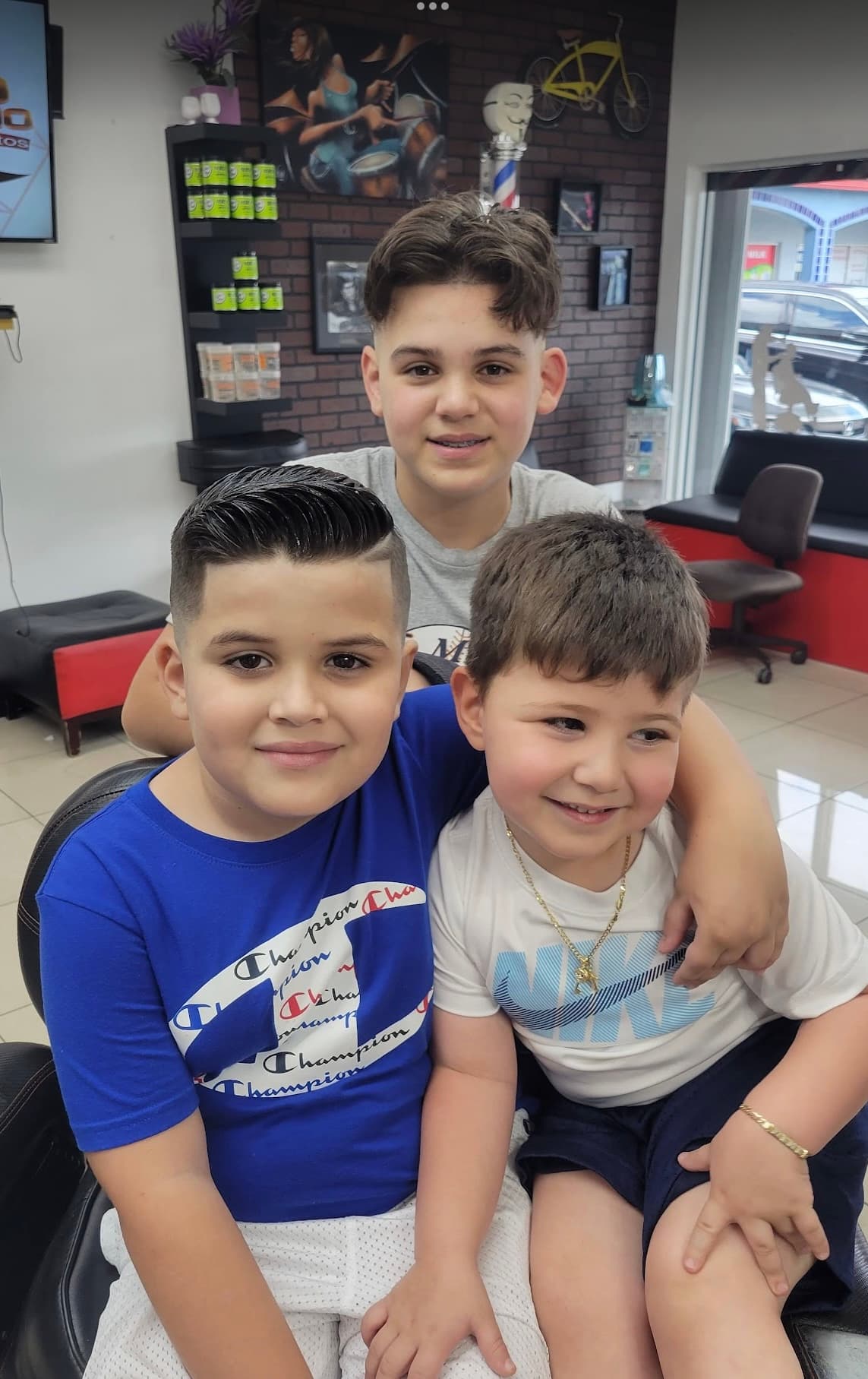 Tres niños con cortes frescos en el interior de La Fe Barbershop