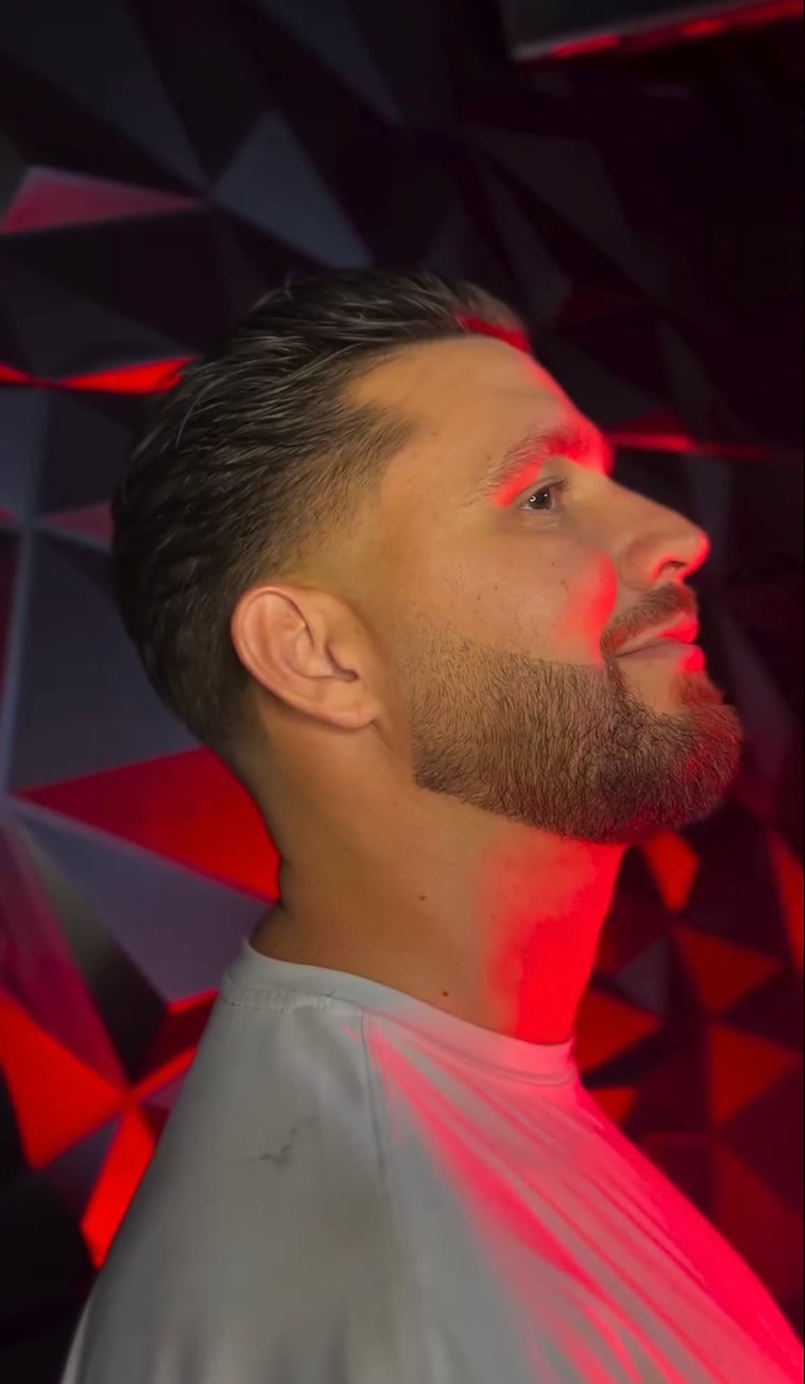 Perfil con taper fade y barba bajo iluminación roja en La Fe